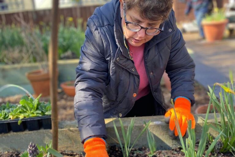 A lady enjoying learning new gardening skills in Wantage Market Garden in Oxfordshire