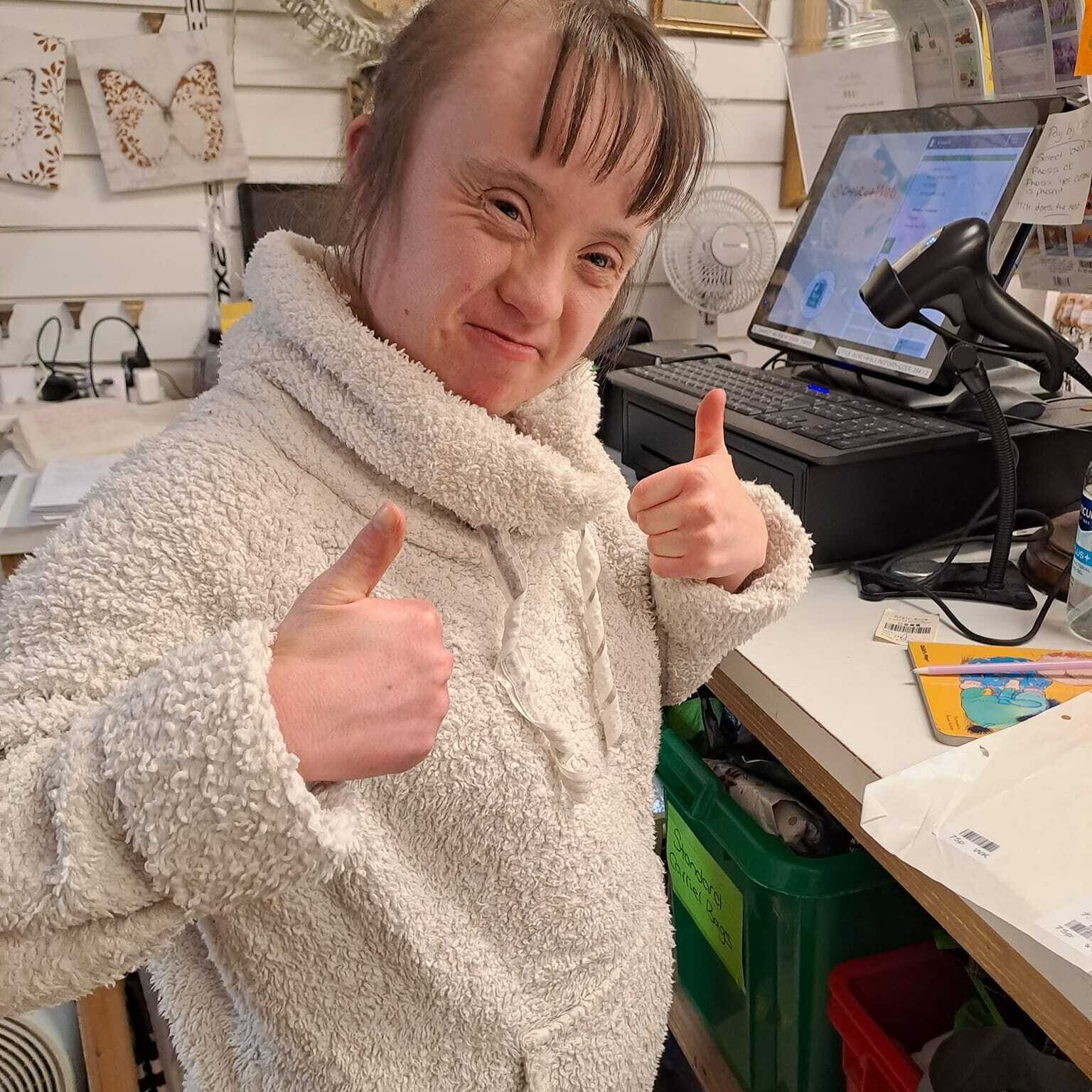A lady enjoying her work at the charity shop and giving a thumbs up - Employment support in Oxfordshire, Style Acre