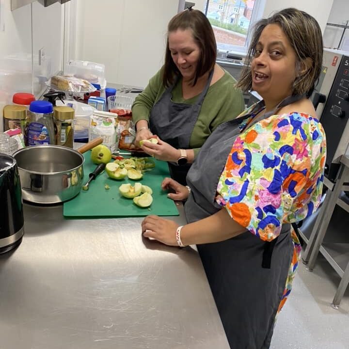 A lady learning cooking skills in a large kitchen with community support