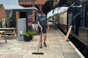 A gentleman sweeping a railway station - supported work programme in Oxfordshire