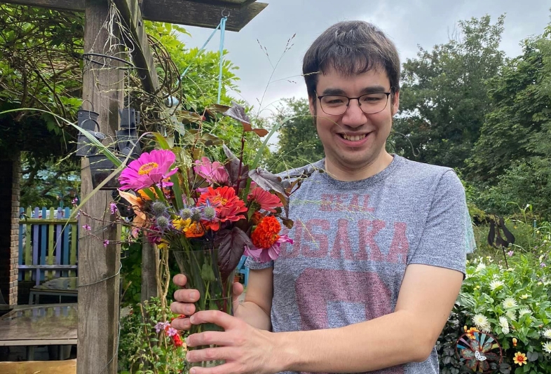 AA person volunteering at a garden holding flowers