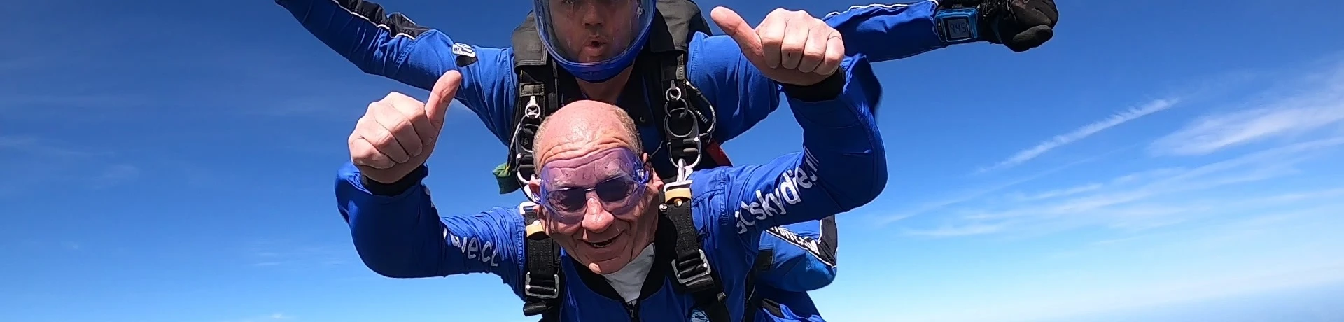 A gentleman doing a sky dive with his thumbs us fundraising for Style Acre.