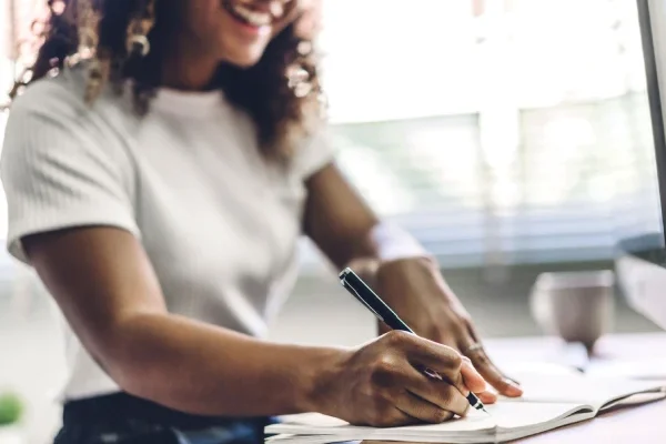 A lady at a desk writing to leave a gift in her will. Fundraising for Style Acre.