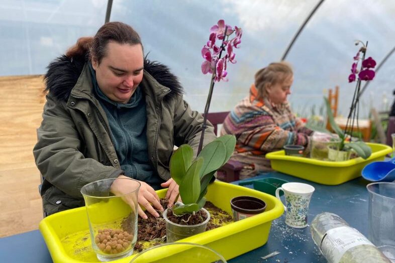 Two ladies potting up orchids in a Polly Tunnel