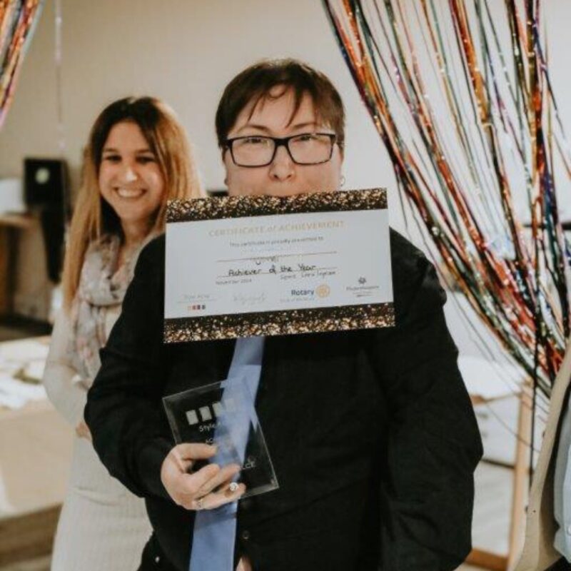 Skylar holding her achiever of the year certificate and award, celebrating his amazing achievement