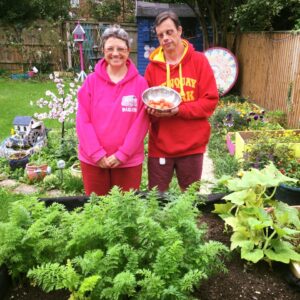 Two people supported by Style Acre next to their vegetable patch