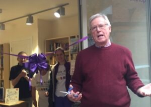 John Craven, OBE cutting a purple ribbon to officially open The Little Book Shop