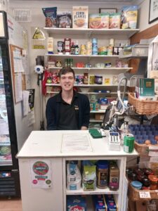 Dom sitting at the serving counter smiling.