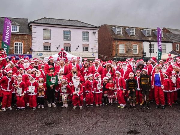 Group of adults and children dressed in Santa suits