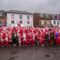 Group of adults and children dressed in Santa suits