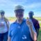 Person giving thumbs up stood with two people and countryside behind them