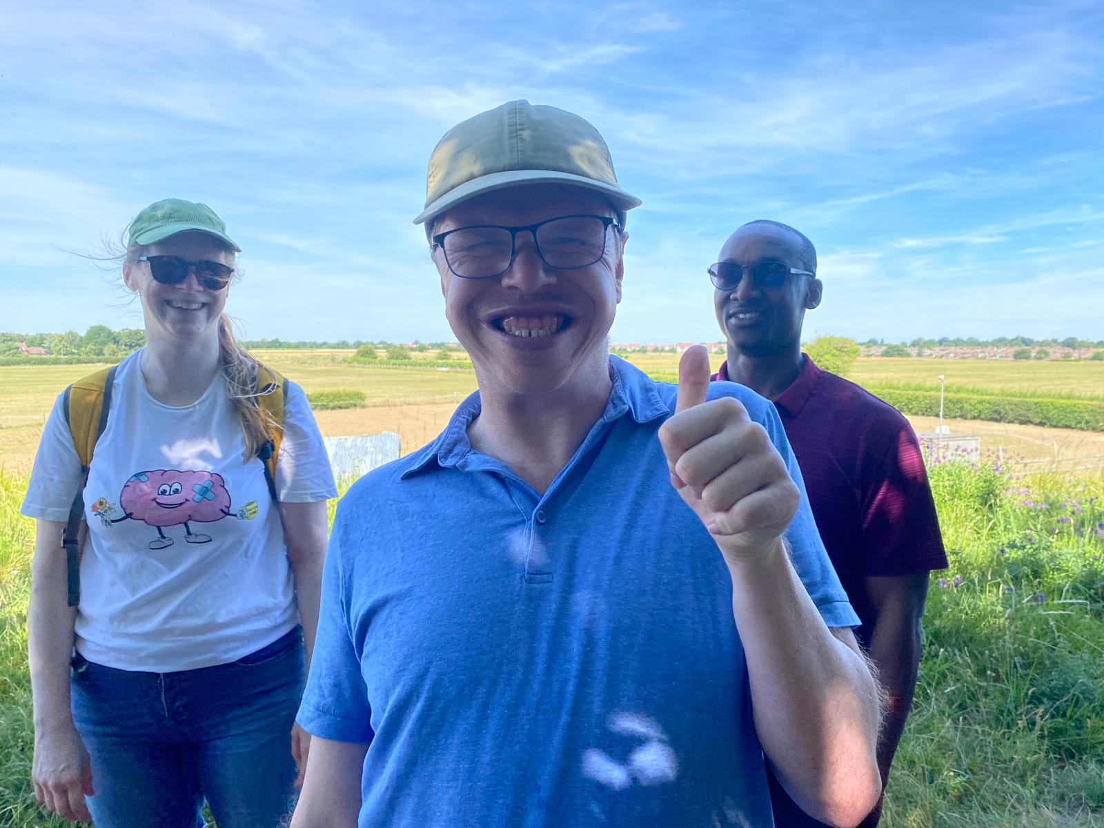 Didcot walk Matty Person giving thumbs up stood with two people and countryside behind them