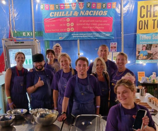 A team of 10 volunteers standing together at the Truck Festival chilli nacho stand.