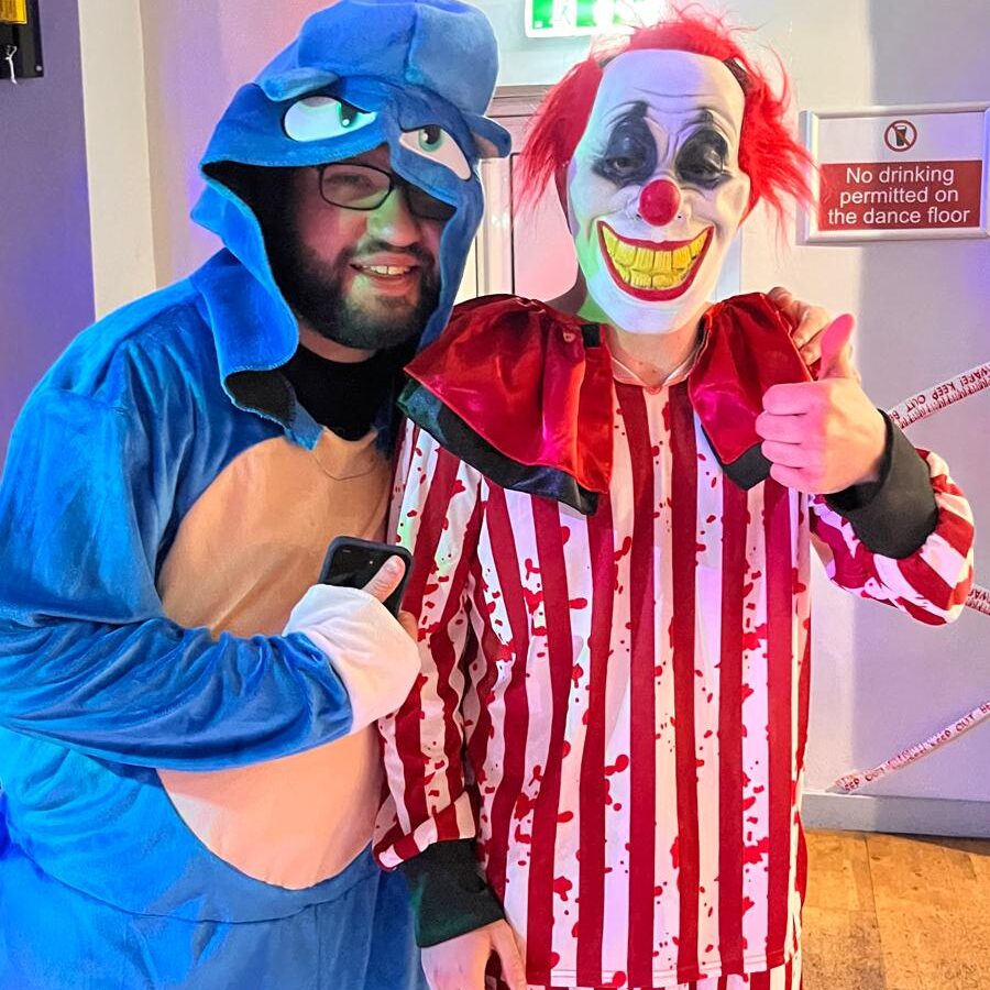 To men standing together in a Sonic the Hedgehog costume and scary clown costume.