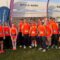 Team of runners standing together in orange running vests