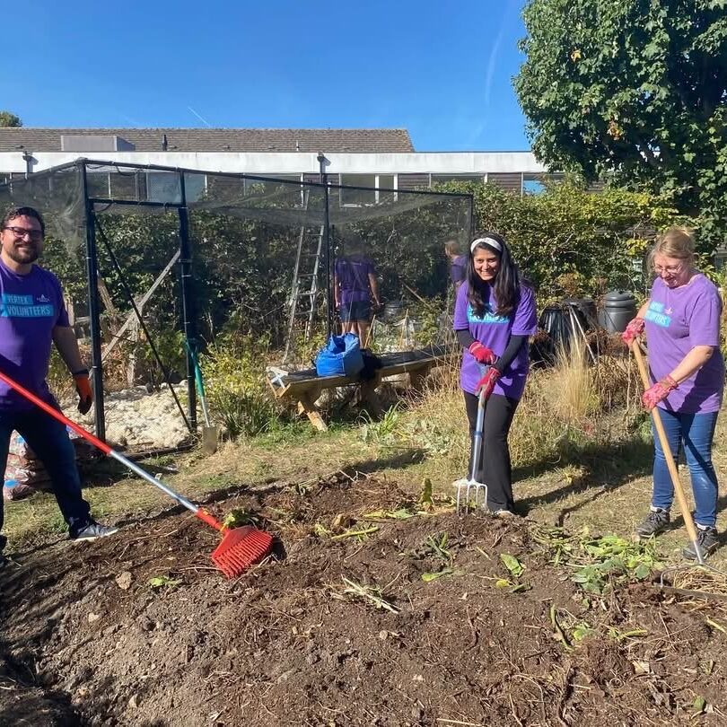 3 people, 2 women and a man working on a flower bed
